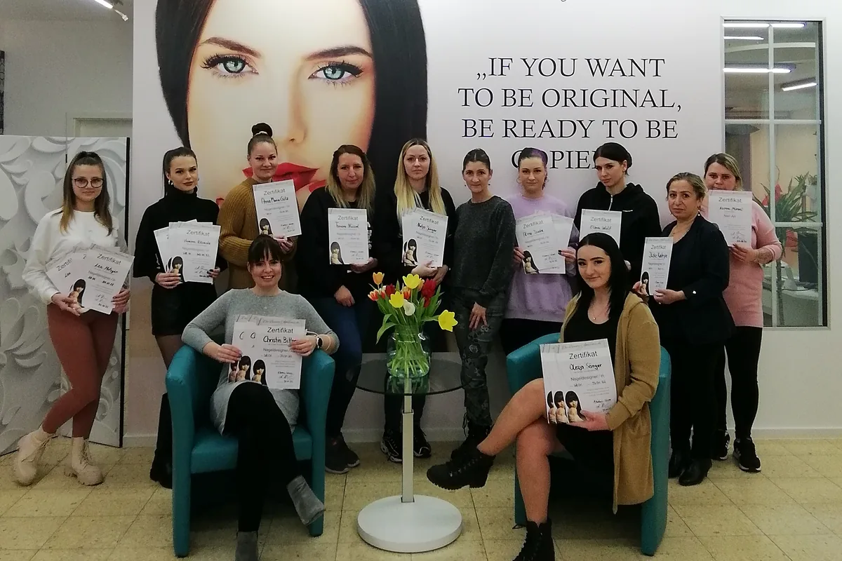 Absolventinnen einer Nageldesign-Ausbildung halten am letzten Kurstag ihre Zertifikate in die Kamera.